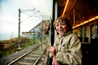 A very excited young boy looks out of a train window.